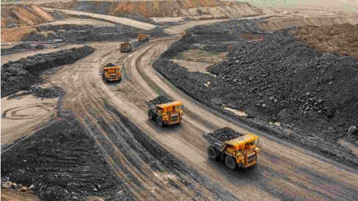 Three large yellow load haul trucks at the Longonjo rare earths mine in Angola