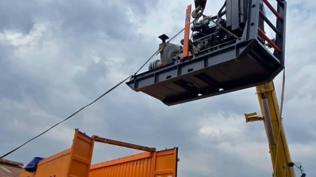 The trailer-mounted detwatering pump being loaded into an open top container