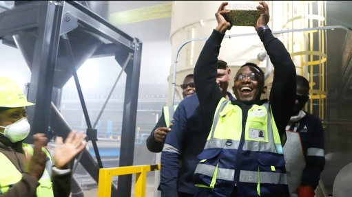 Beaming plant manager holds up Far West's first doré gold bar.