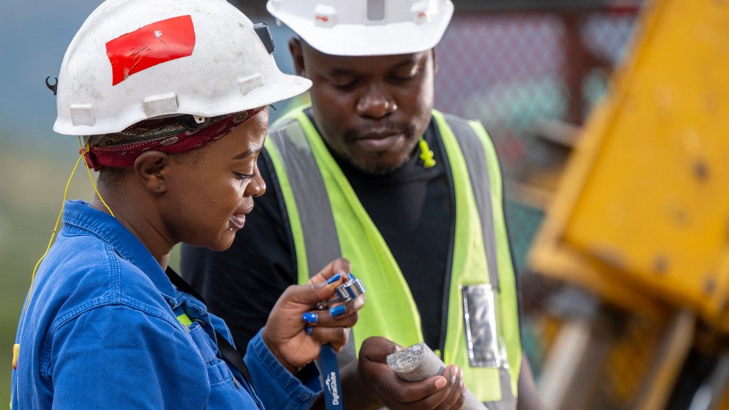 A woman in PPE assesing a core sample being held by a man