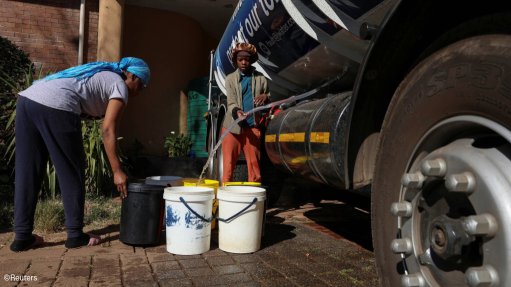 People filling buckets of water from a water tanker