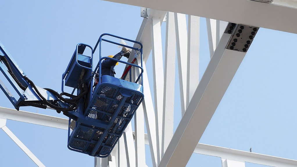 Image of a worker in a crane applying fire protection coating to a steel structure