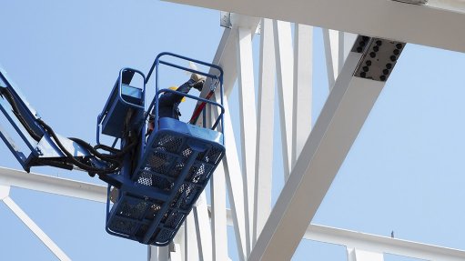 Image of a worker in a crane applying fire protection coating to a steel structure