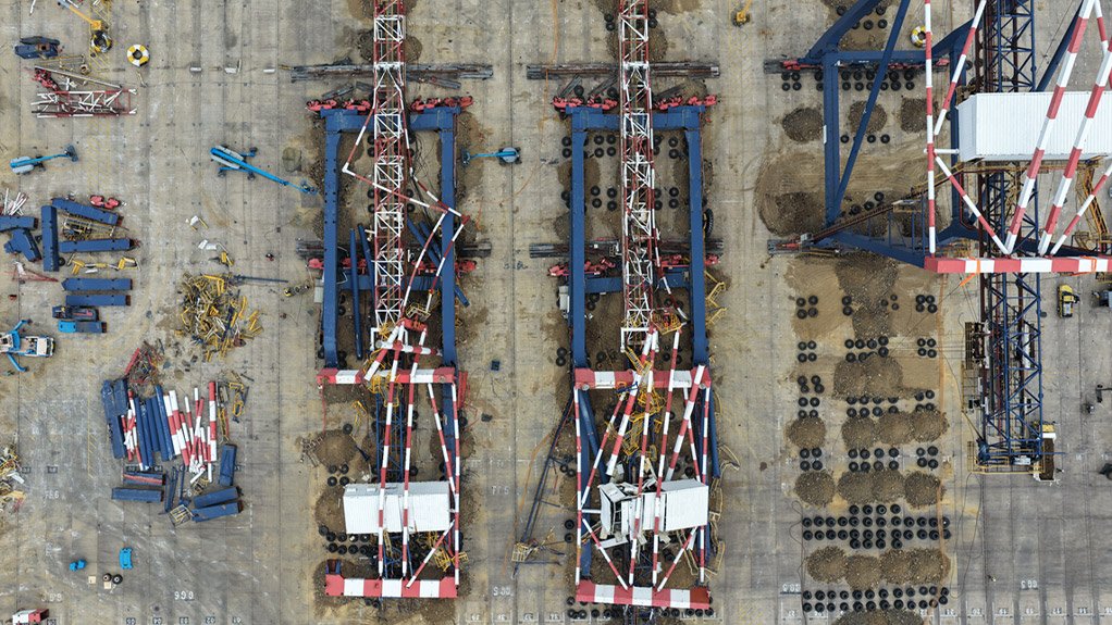 Two of the felled cranes lie on their impact mattresses, with cut sections stacked alongside and a third crane still standing over its landing bed.



