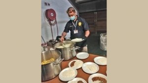 Law Enforcement Officer Jason Rondganger dishes up food at the temporary homeless shelter at Rosemoor stadium