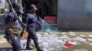 An image of police officers walking past property damaged in the July 2021 unrest in South Africa