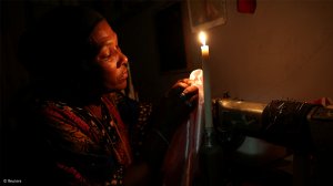 A woman using a candle during loadshedding 