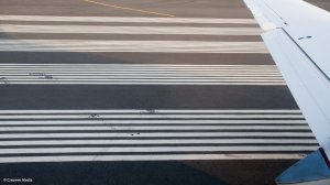 The wing of an aeroplane, with a runway in the background