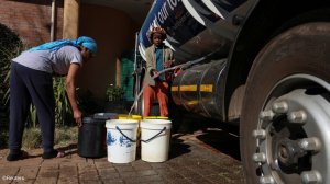 People filling buckets of water from a water tanker